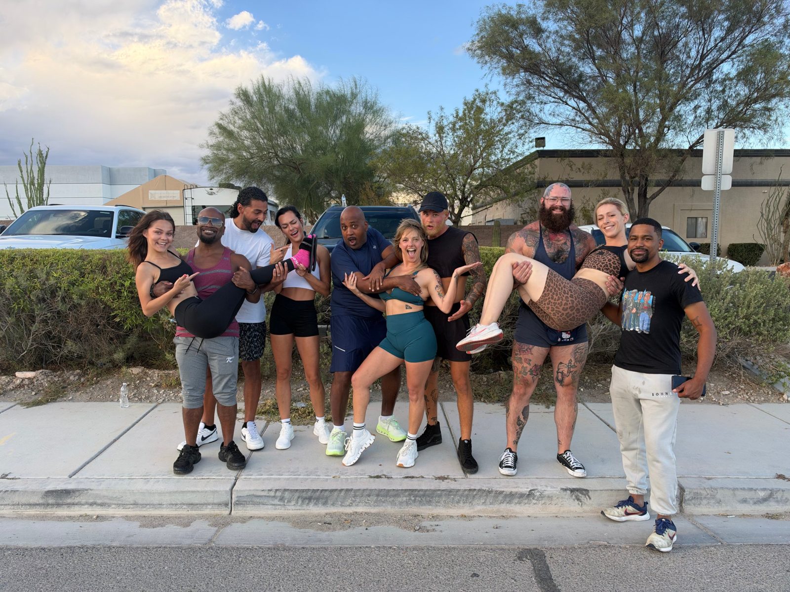 Run Club members posing on the sidewalk, two carrying partners